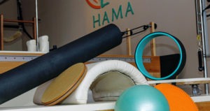 Com o fundo do interior do Studio Hama alguns instrumentos de pilates, como bolas, almofadas e suportes estão dispostos um ao lado do outro